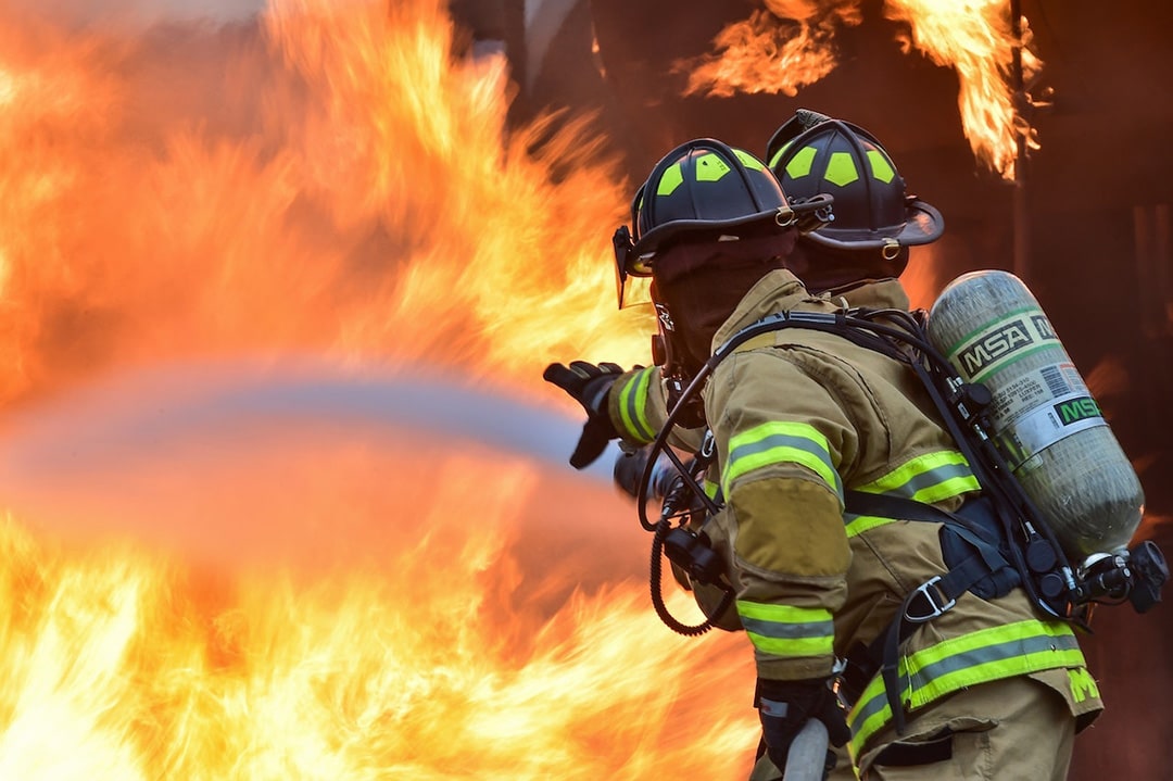 imagem destacada do artigo post "Quem pode ser perito em incendio. Quanto ganha e como ser um". Na imagem temos dois bombeiros apagando um grande incêndio