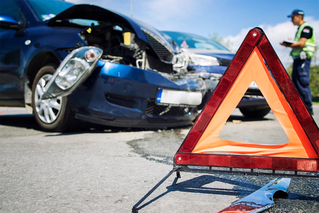 imagem destacada do artigo post Quem pode ser perito em trânsito? 6 motivos para ser um. Na imagem temos dois carros batidos, um triângulo de trânsito e um homem com colete amarelo fazendo a perícia