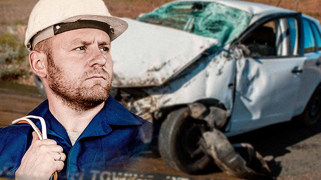 A imagem contém no primeiro plano a parte superior de um engenheiro de capacete branco e camisa azul, olhando para o lado, e ao fundo no background a imagem desfocada de um carro acidentado na pista.